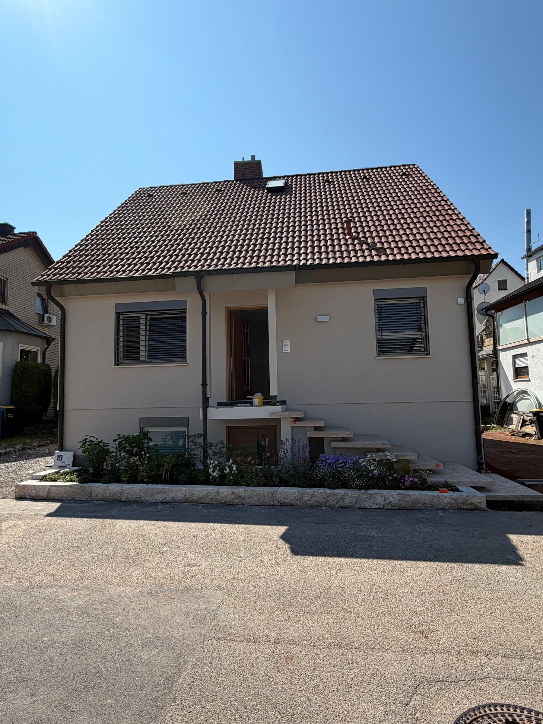 Saniertes Einfamilienhaus mit rotem Ziegeldach von der Straße aus